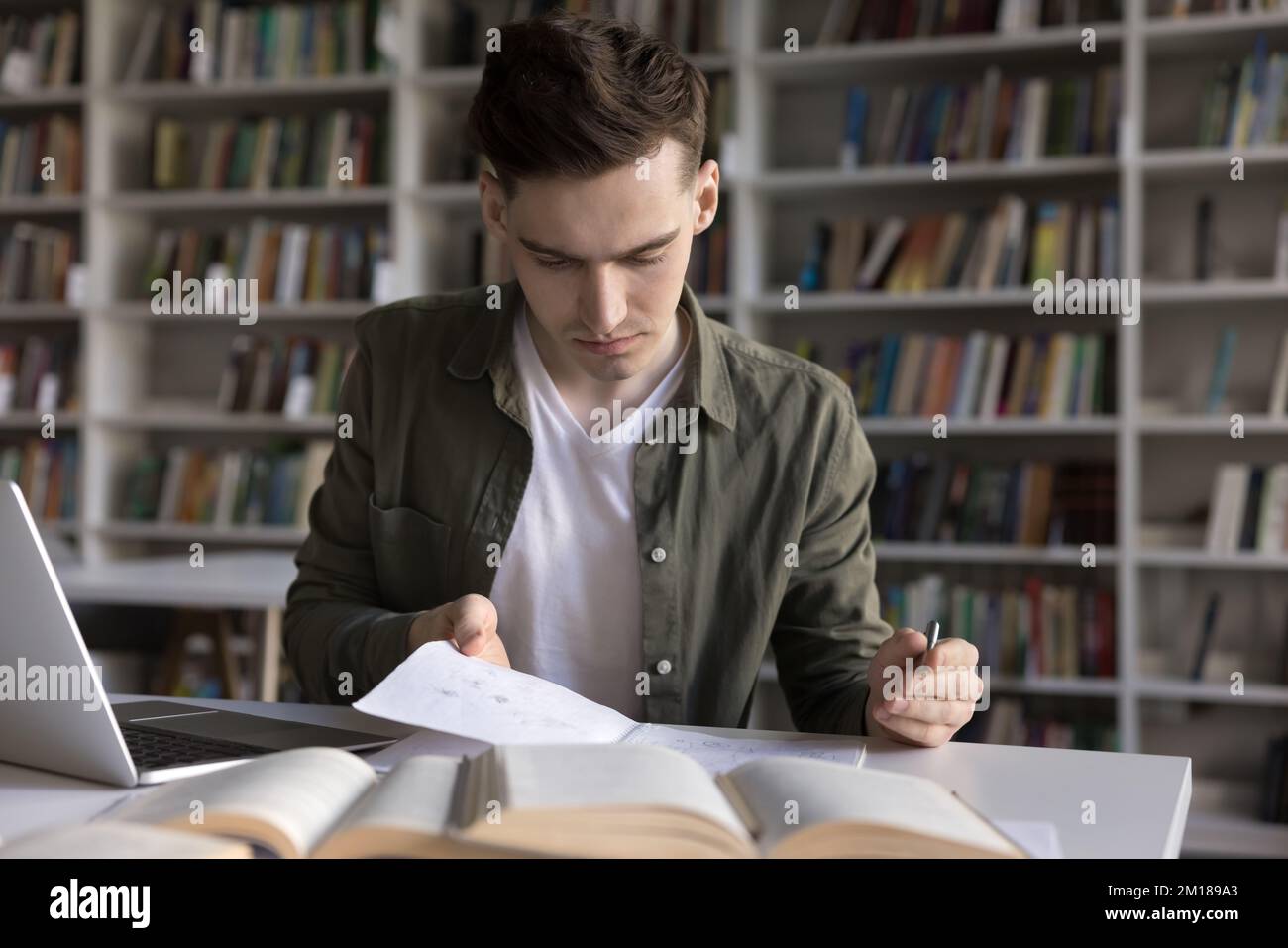 Focused serious student guy writing webinar summary, reading notes Stock Photo