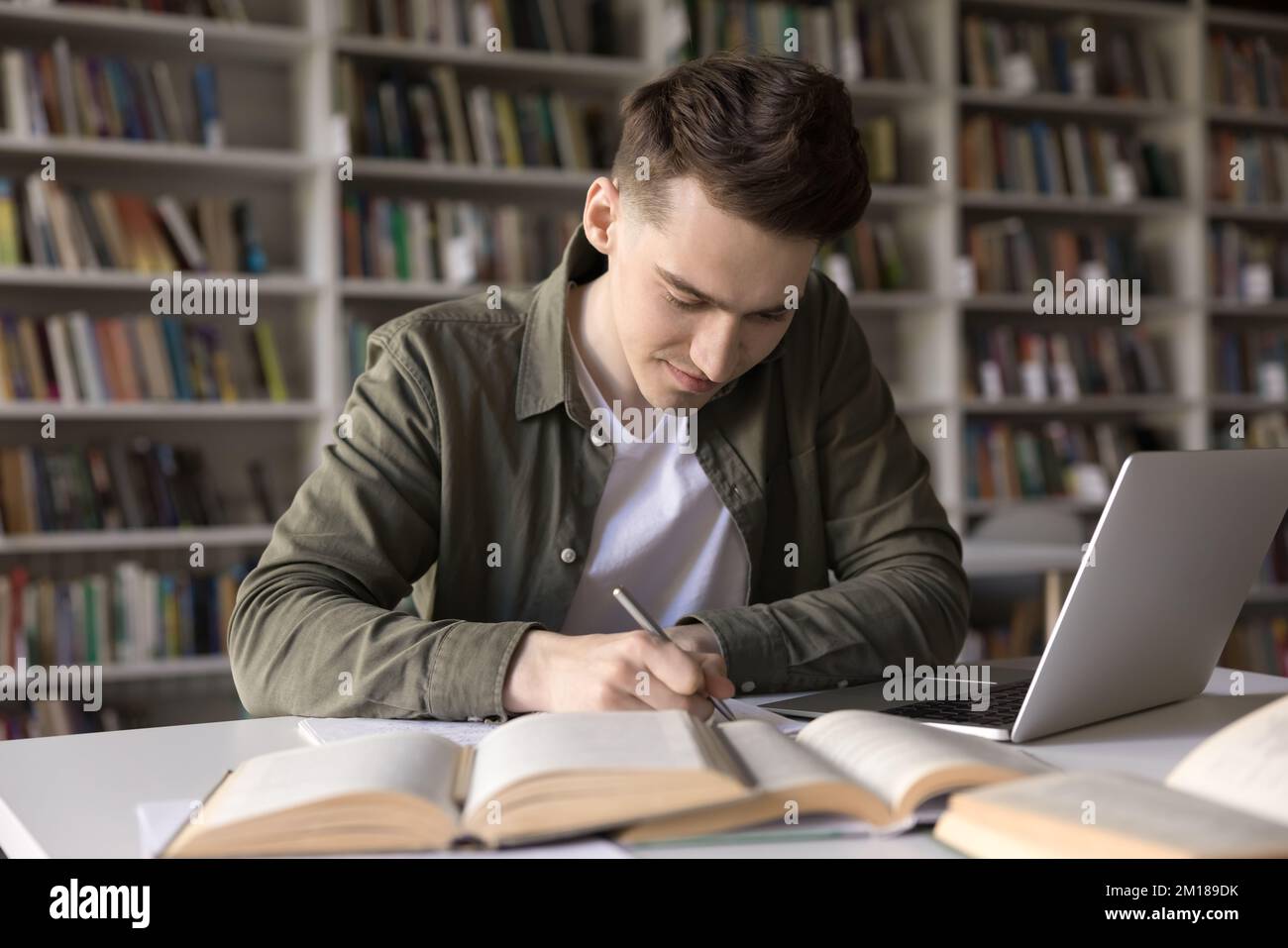 Positive busy hardworking student guy writing draft, notes Stock Photo