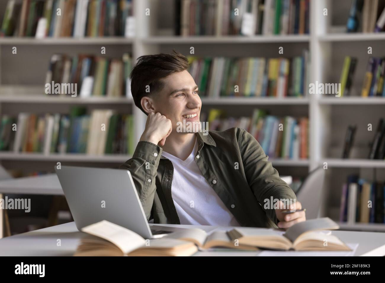 Happy dreamy student guy working on scientific article Stock Photo