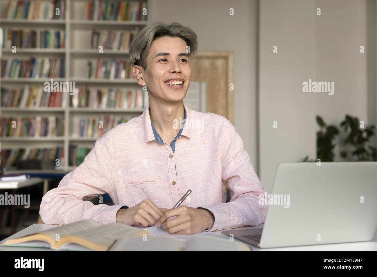 Cheerful smart Asian student guy working on article Stock Photo