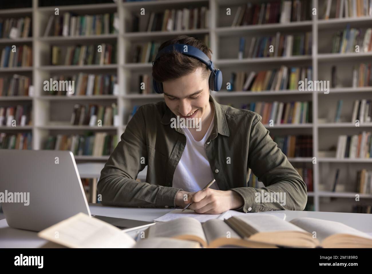 Positive student guy in wireless headphones listening online learning course Stock Photo