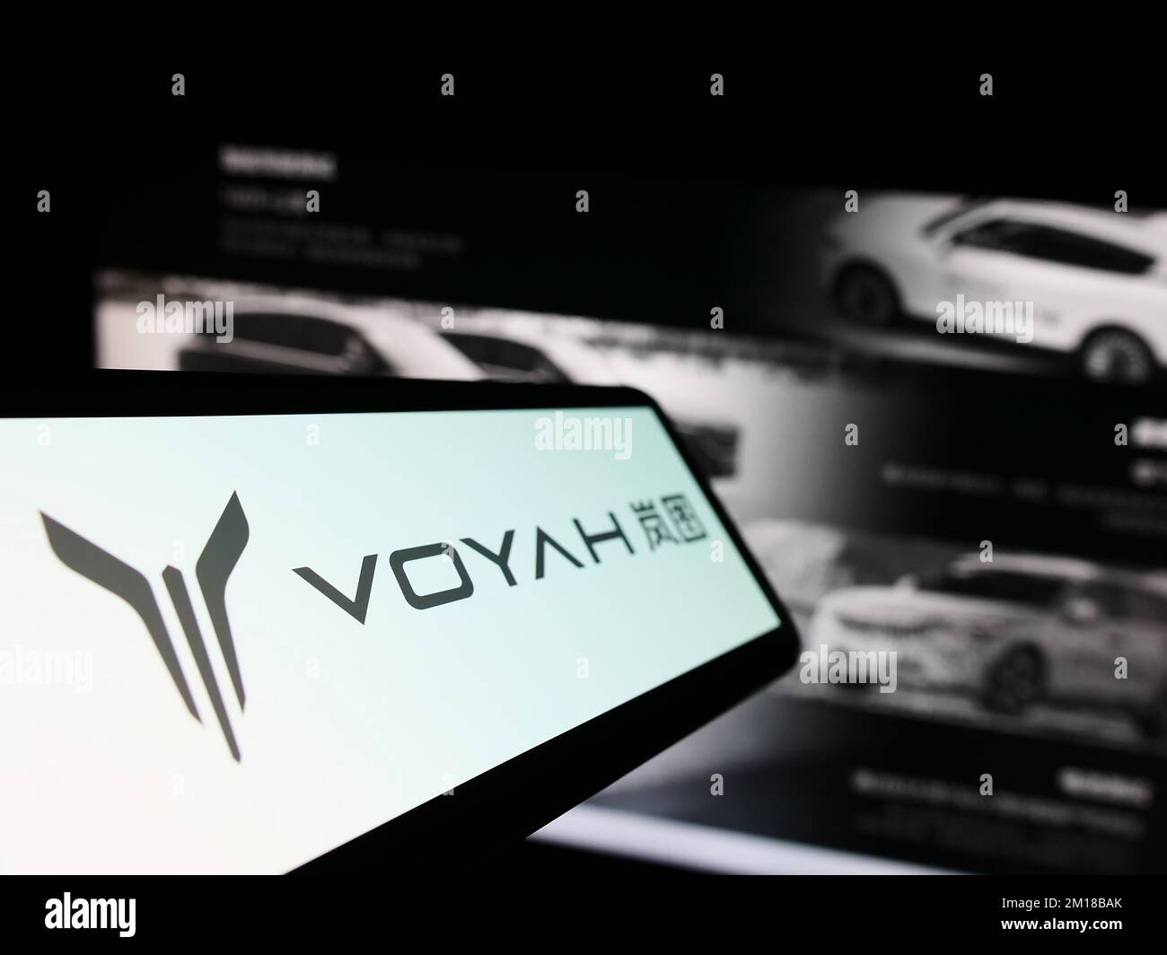 Smartphone with logo of Chinese luxury car manufacturer Voyah on screen in front of company website. Focus on center-left of phone display. Stock Photo