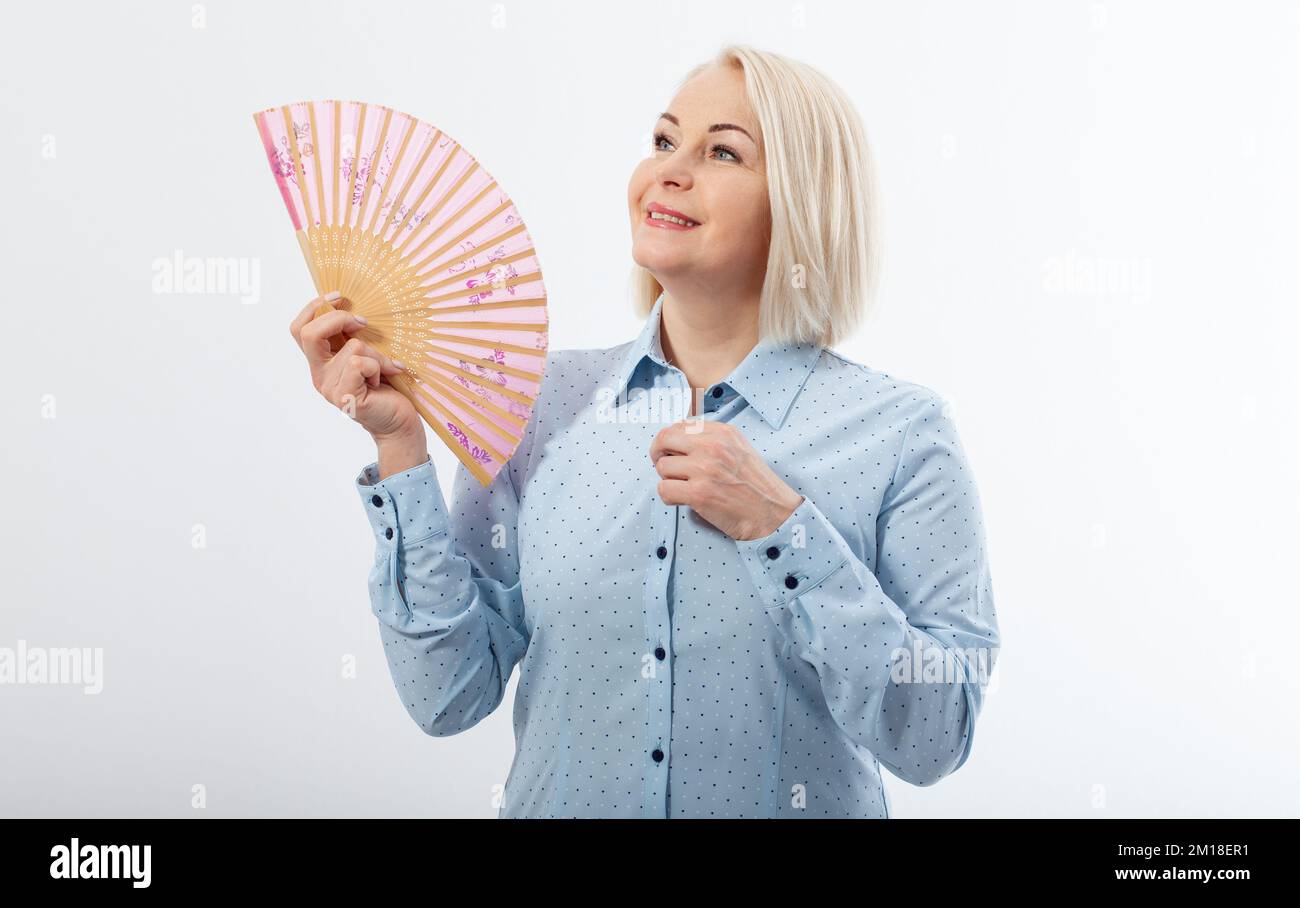 Beautiful middle aged woman with menopause blowing by fan. Hormone replacement therapy and mature woman healthcare. Mid age happy women lifestyle Stock Photo