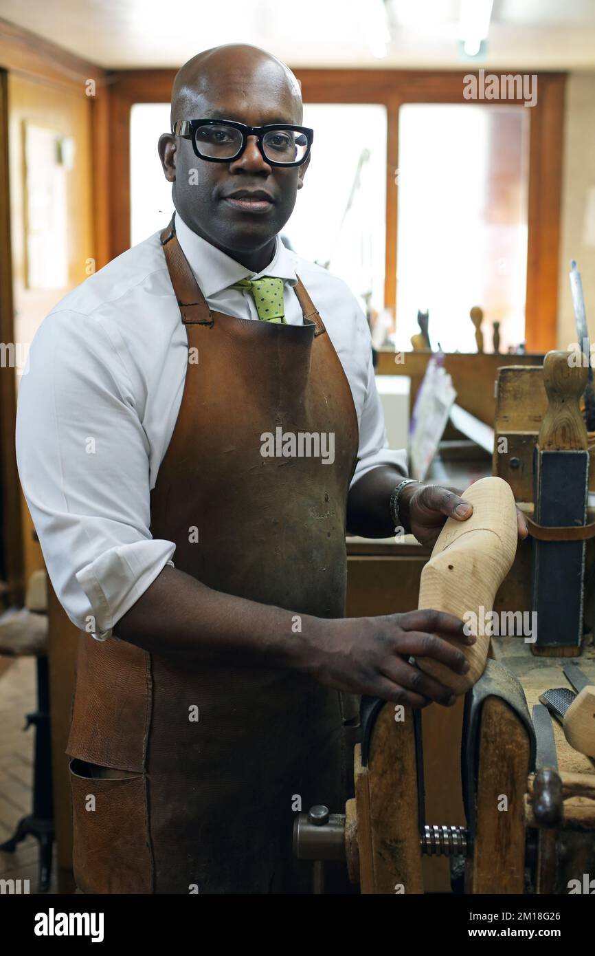 Portrait of a shoemaker at Lobb Shoes, St James, London holding a ...