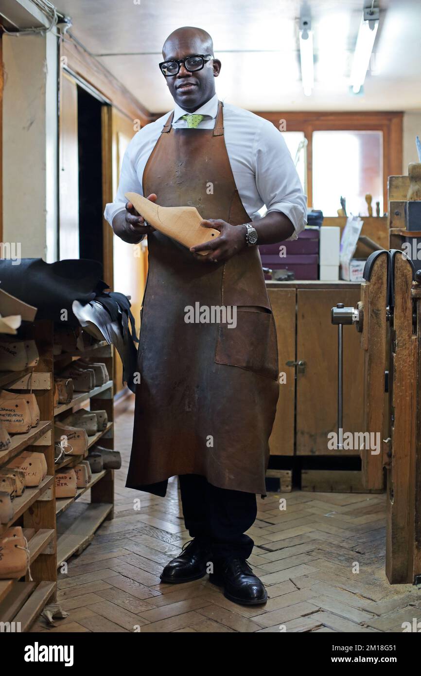 Portrait of a shoemaker at Lobb Shoes, St James, London holding a ...