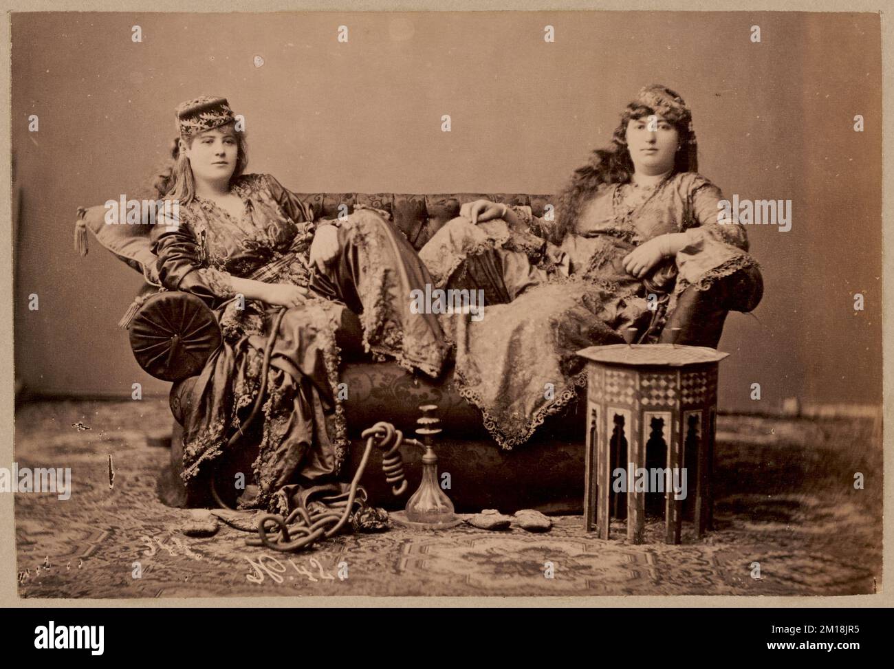 Studio portrait of two women in traditional Turkish dress , Clothing & dress, Water pipes Smoking. Nicholas Catsimpoolas Collection Stock Photo