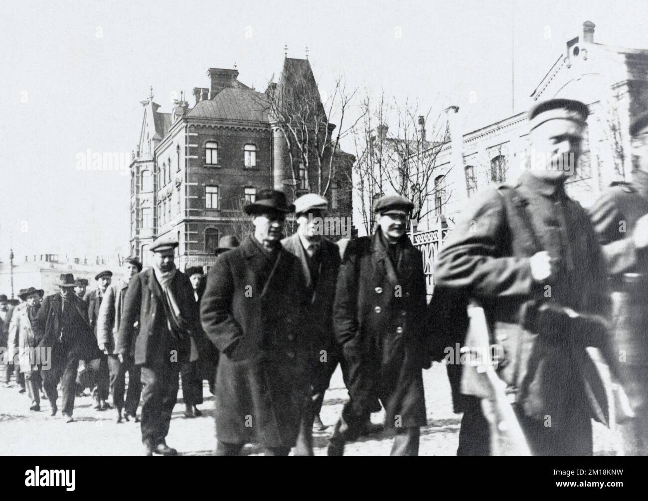 German soldiers leading a column of military-aged men through an occupied French town during the First World War, likely to be interned. Stock Photo