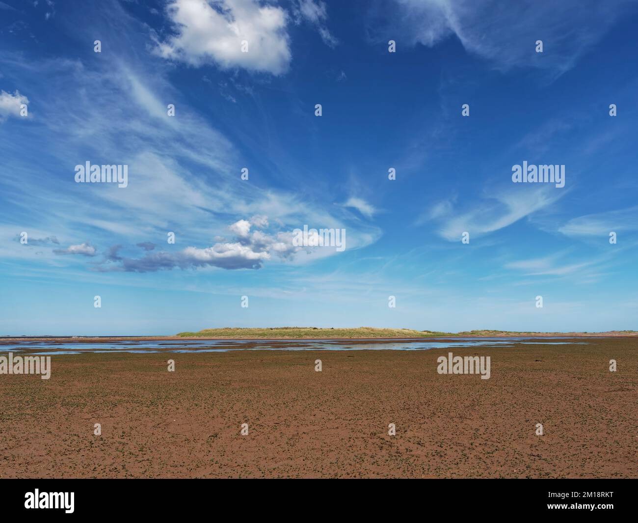 The pools and wet sand of the Headwell Sands at Tentsmuir Point as the tide recedes beneath a dramatic blue and cloud filled sky. Stock Photo