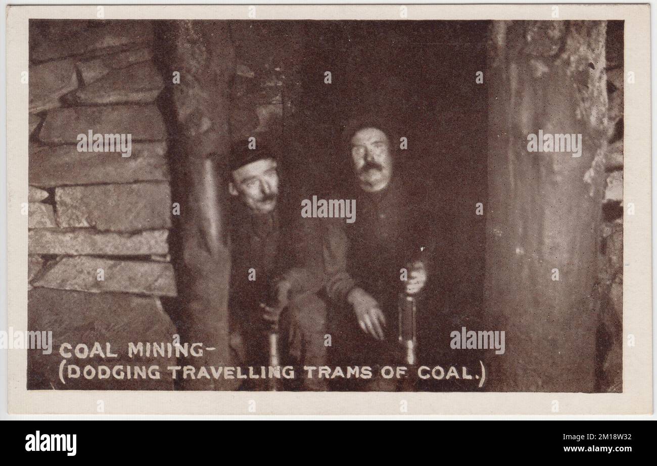 Coal mining - dodging travelling trams of coal. Early 20th century photograph of two miners, holding miners' lamps, sitting in a dugout to the side of the pit shaft to avoid being run over by trams transporting coal out of the mine. The image was one of a set of photos published as postcards by M. Brookes of Pontypridd, South Wales Stock Photo