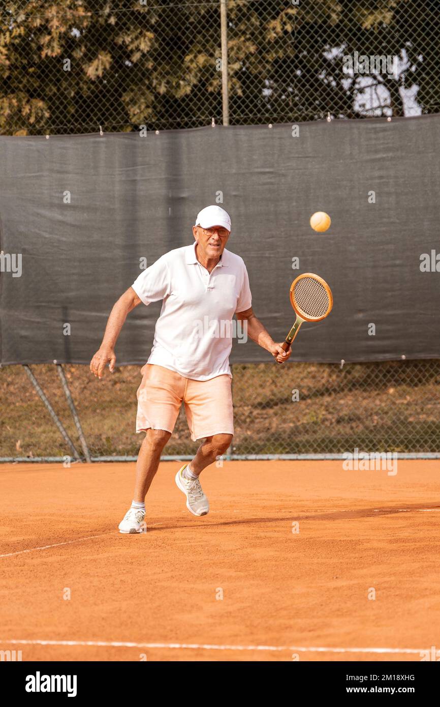 Senior tennis player dressed in sportswear in action on a clay tennis court  - retired wellness concept Stock Photo - Alamy