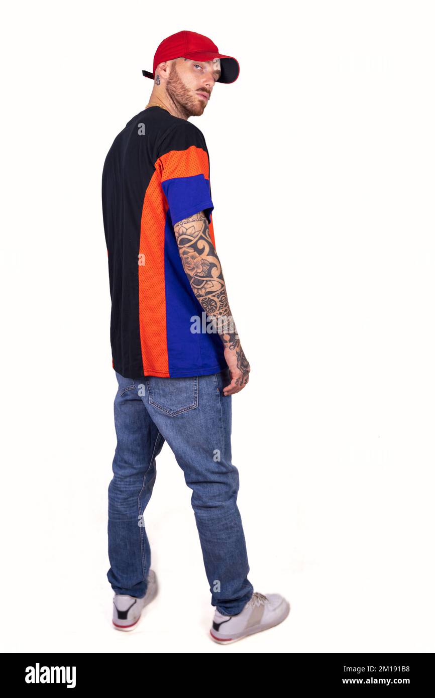 tattooed rap singer posing in studio wearing red cap on a white background Stock Photo