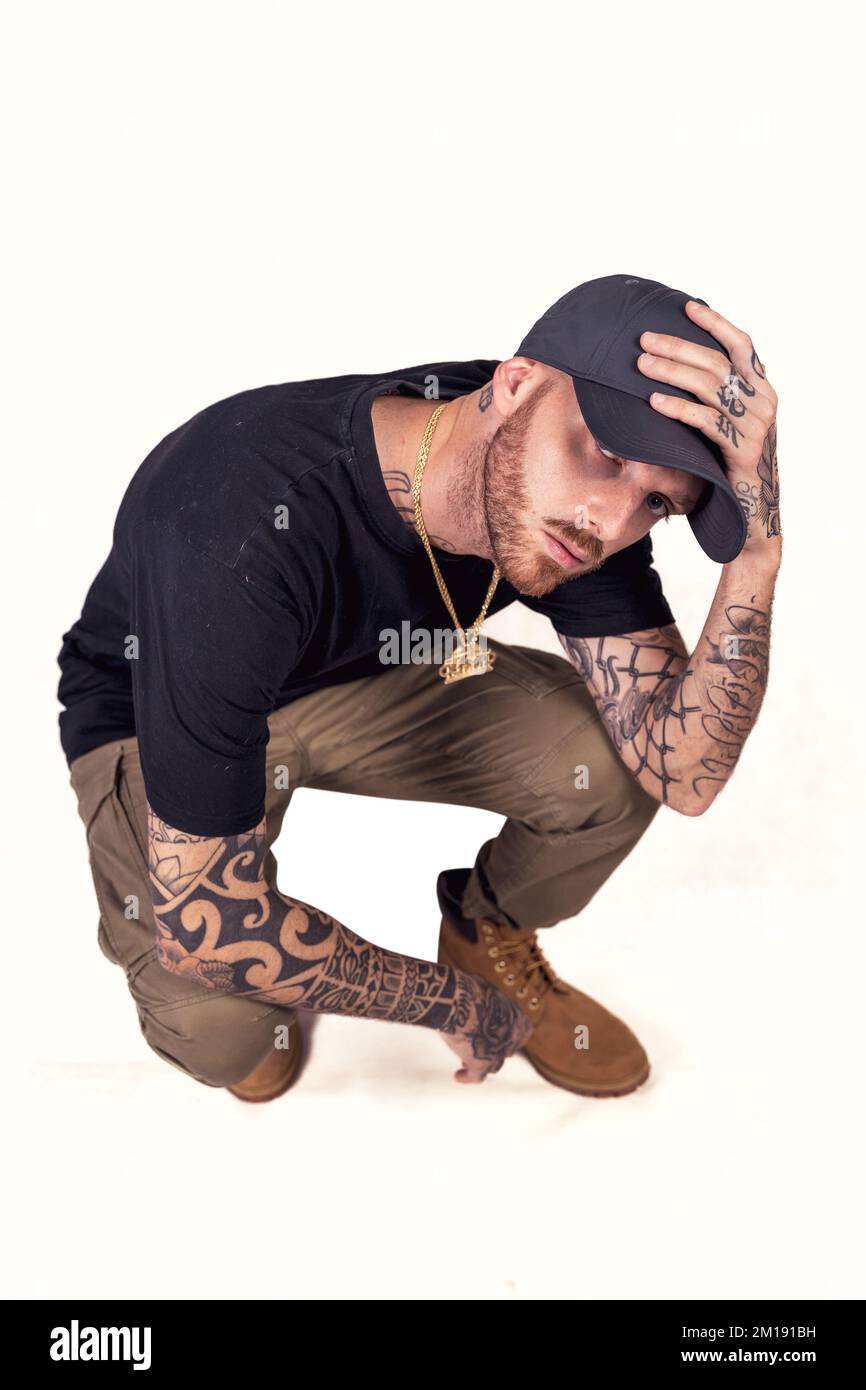 tattooed rap singer posing in studio wearing black clothes on a white background Stock Photo