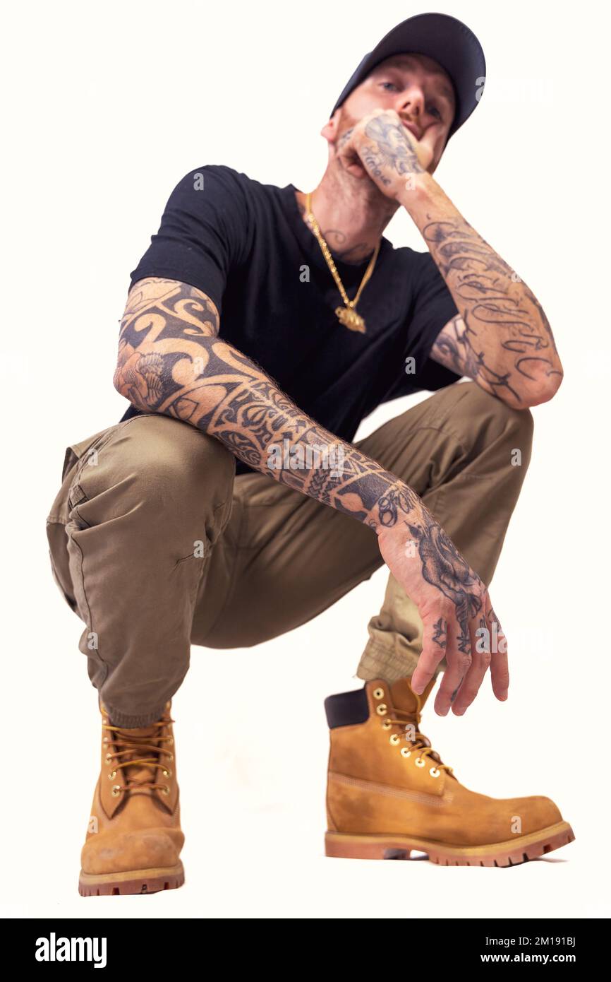 tattooed rap singer posing in studio wearing black clothes on a white background Stock Photo