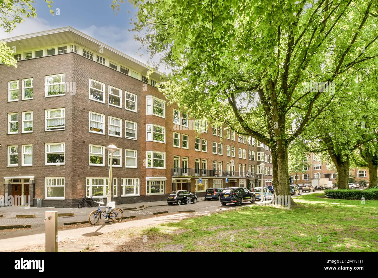 an apartment building with trees in the front and cars parked on the ...