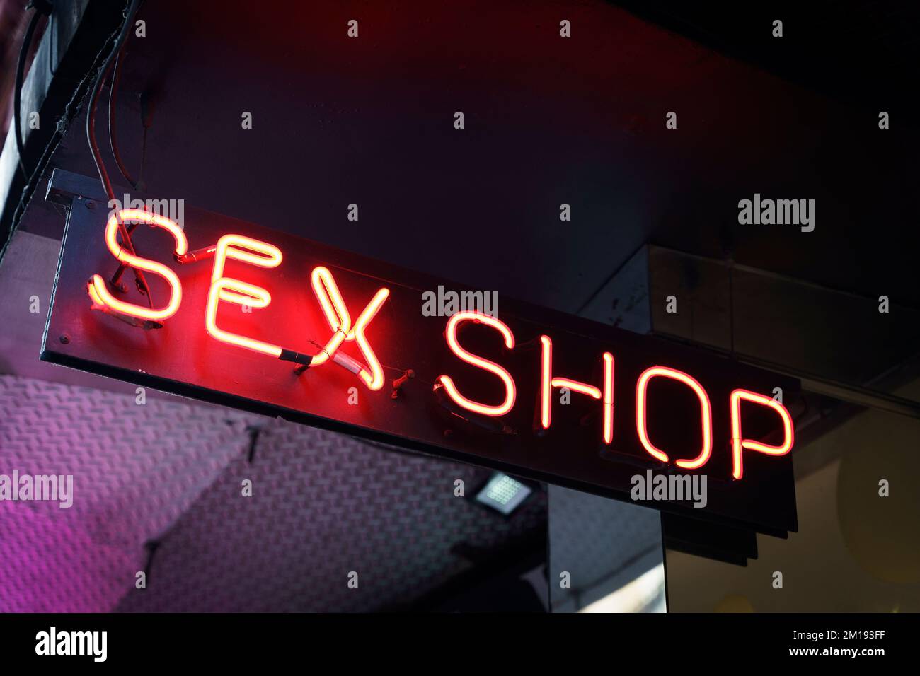 Neon sign of a sex shop on a city street. Atmospheric glowing red inscription on the evening street in the tourist quarter. High quality photo Stock Photo