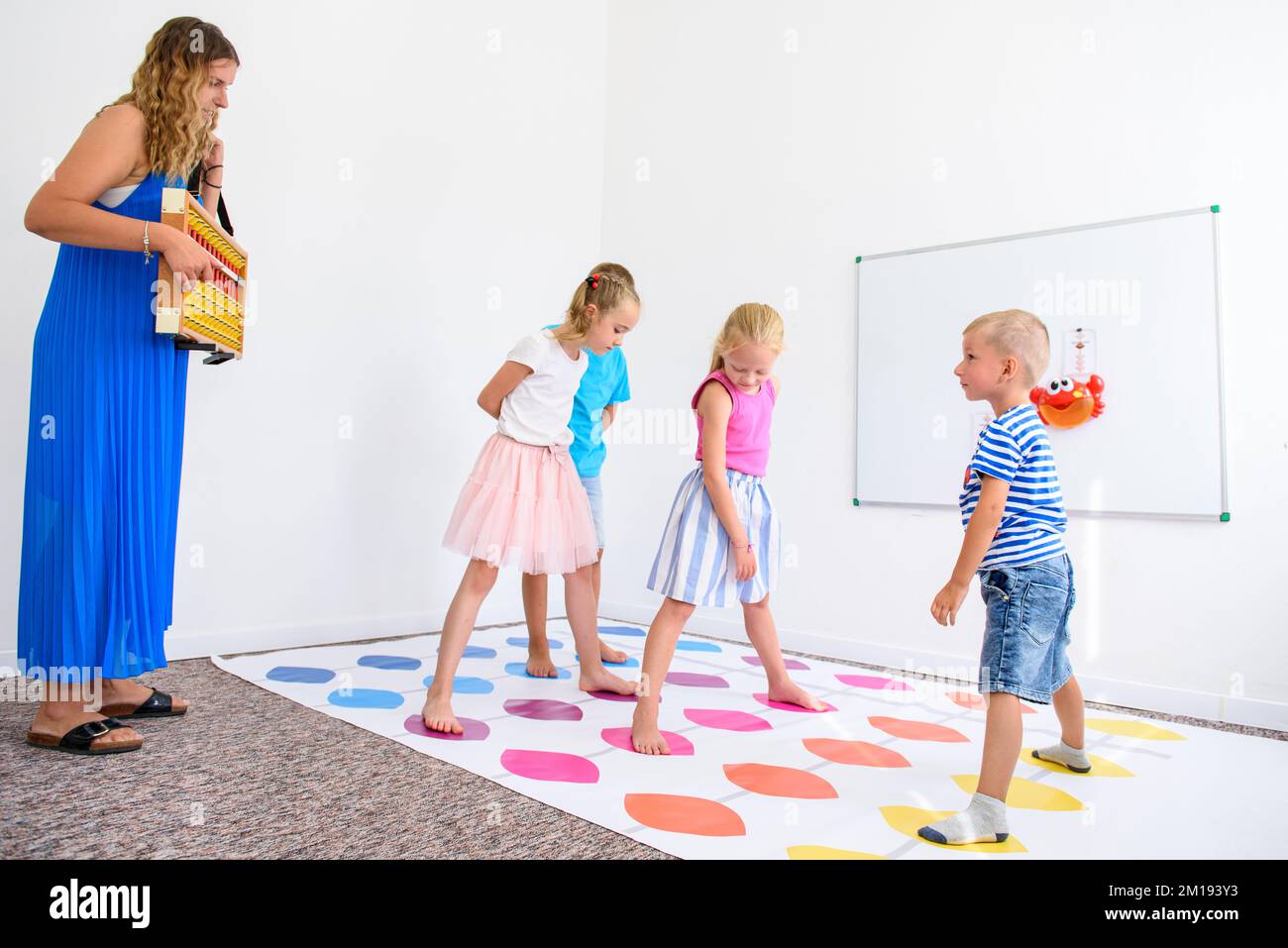 Child occupational therapy session. Group of children doing playful exercises with their therapist. Stock Photo