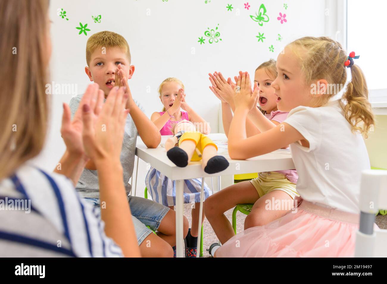 Child occupational therapy session. Group of children doing playful exercises with their therapist. Stock Photo