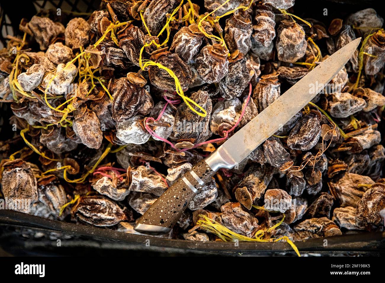 Dried persimmon fruit and a knife beeing sold on the traditional market