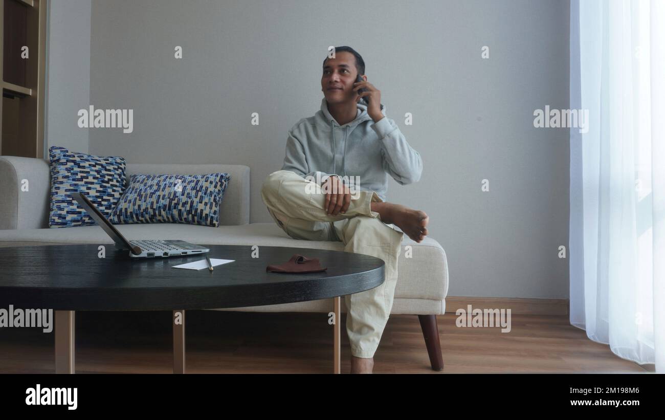 Man using hand phone and laptop notebook in the living room Stock Photo ...