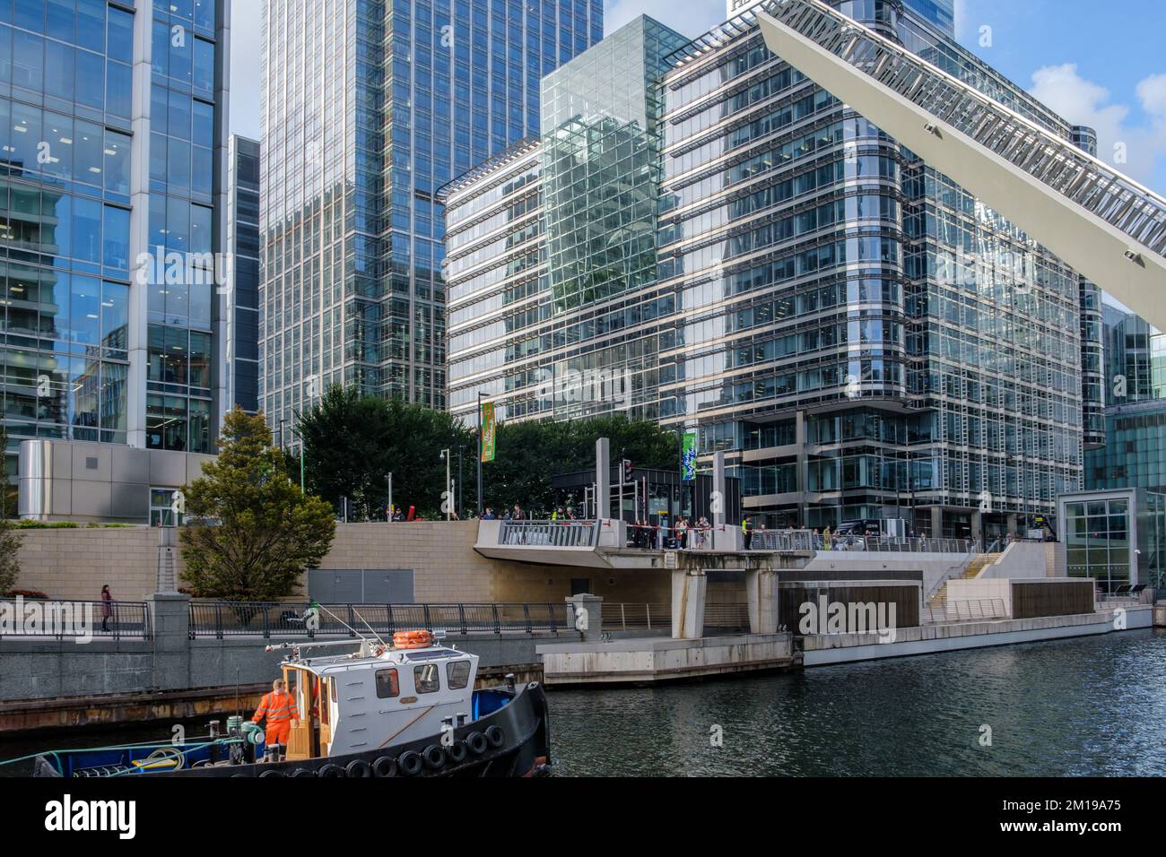 Water Street Bridge at the southern end of Bellmouth Passage opens to allow a boat pass. Facing west, Canary Wharf, East London. Stock Photo