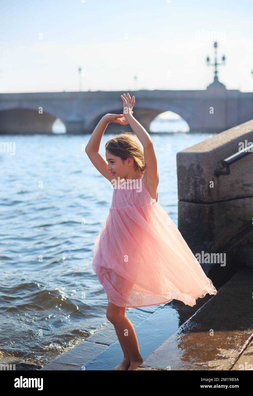 Beautiful Little Girl is dancing with waves at sunset.  Summer Sunny Day,  happy Kids concept Stock Photo