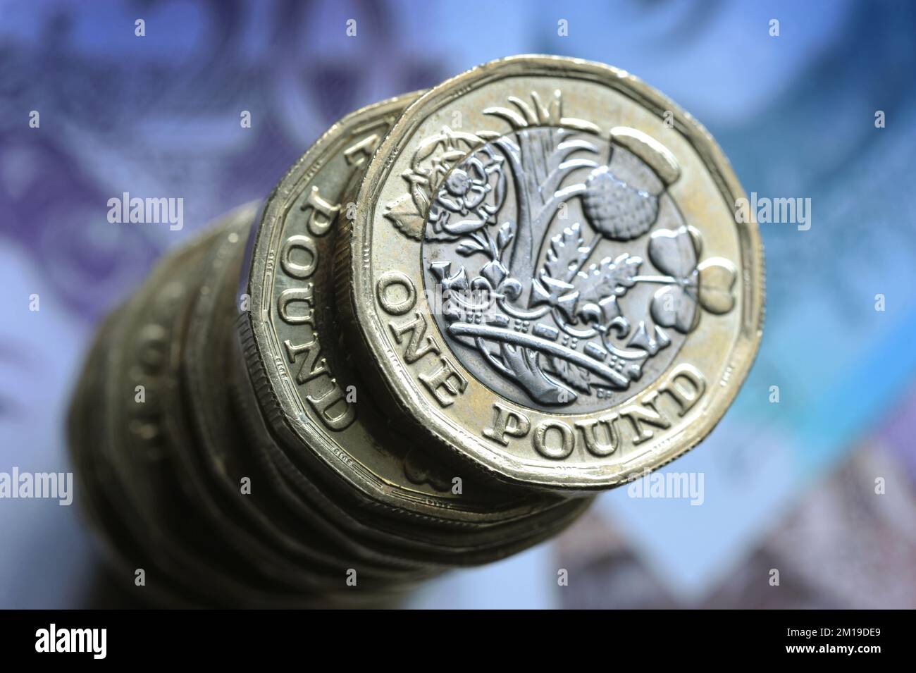 A STACK OF BRITISH ONE POUND COINS ON BRITISH NOTES RE THE ECONOMY RECESSION INFLATION MONEY SPENDING ETC UK Stock Photo
