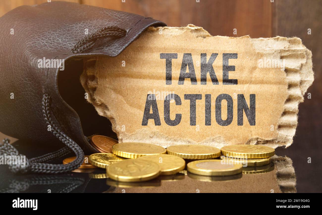 Business and finance concept. On the table is a bag of money from which sticks out cardboard with the inscription - TAKE ACTION Stock Photo
