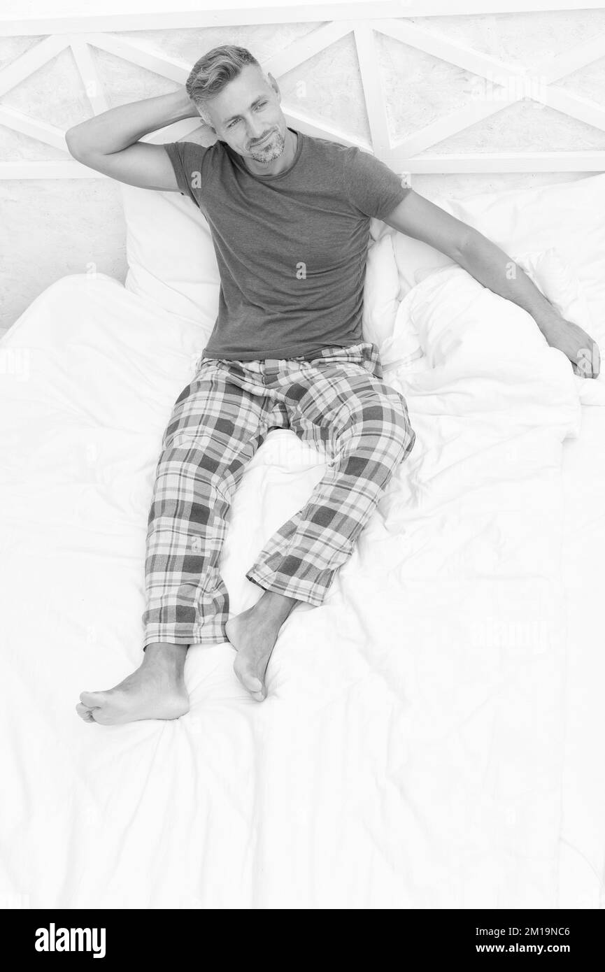 Happy guy in cozy pyjamas daydream resting in bed in morning, daydreaming Stock Photo