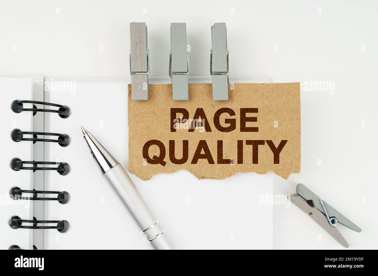 Business and finance concept. On a white background lies a notebook, a pen, clothespins and cardboard with the inscription - Page Quality Stock Photo