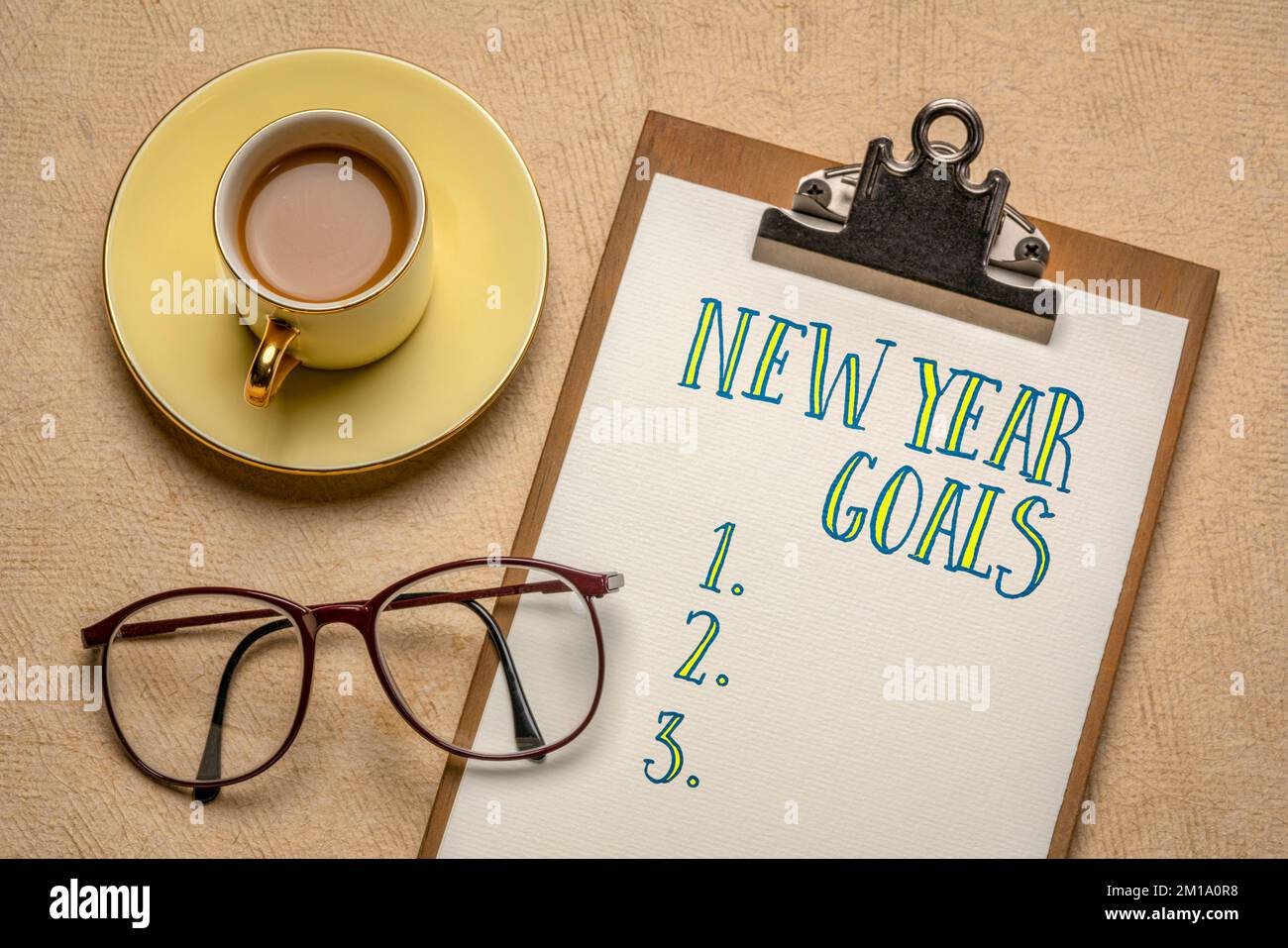 New Year goals list -  handwriting in a clipboard, flat lay with a cup of coffee and glasses, goal setting, business, planning and personal developmen Stock Photo