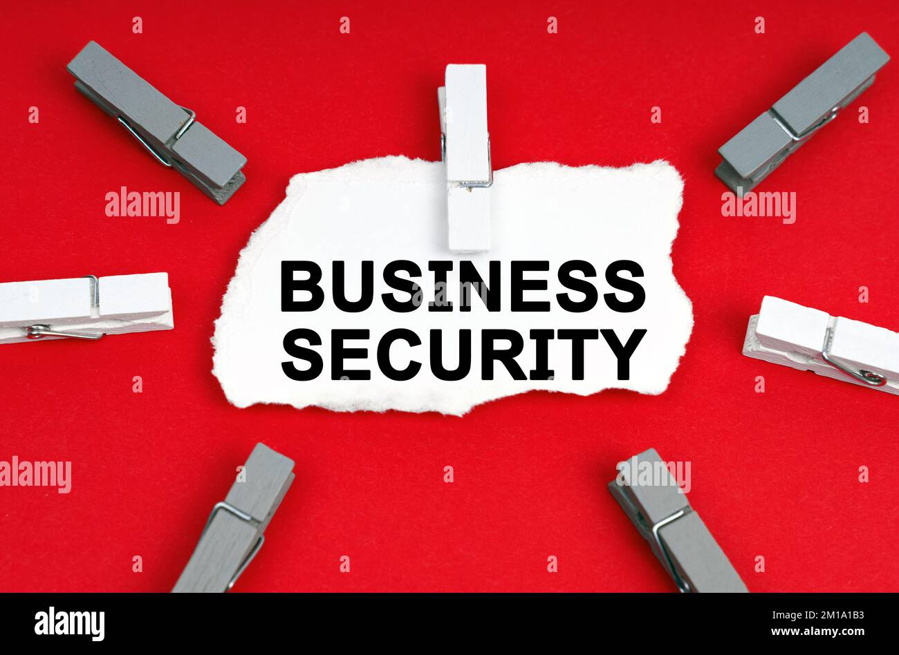 Business and Economics. On a red background, there are clothespins and a piece of paper with the inscription - Business Security Stock Photo
