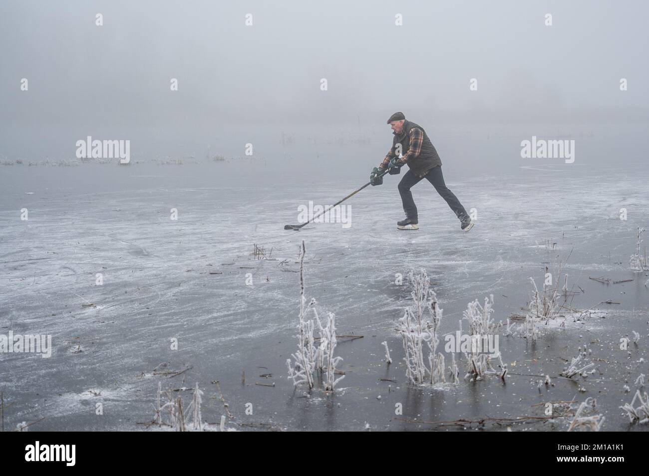 Bluntisham, Cambridgeshire, UK. 11th Dec, 2022. People make the most of the freezing weather skating on the frozen fen washes in freezing fog. After several days of sub zero temperatures the winter weather has allowed the shallow fenland water to freeze over to allow outdoor fen skating. The cold snap is forecast to last into the coming week. Credit: Julian Eales/Alamy Live News Stock Photo