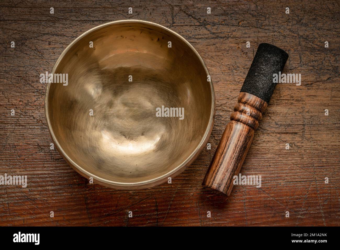 handmade tibetan singing bowl with a mallet, top view against rustic wood, sound therapy for