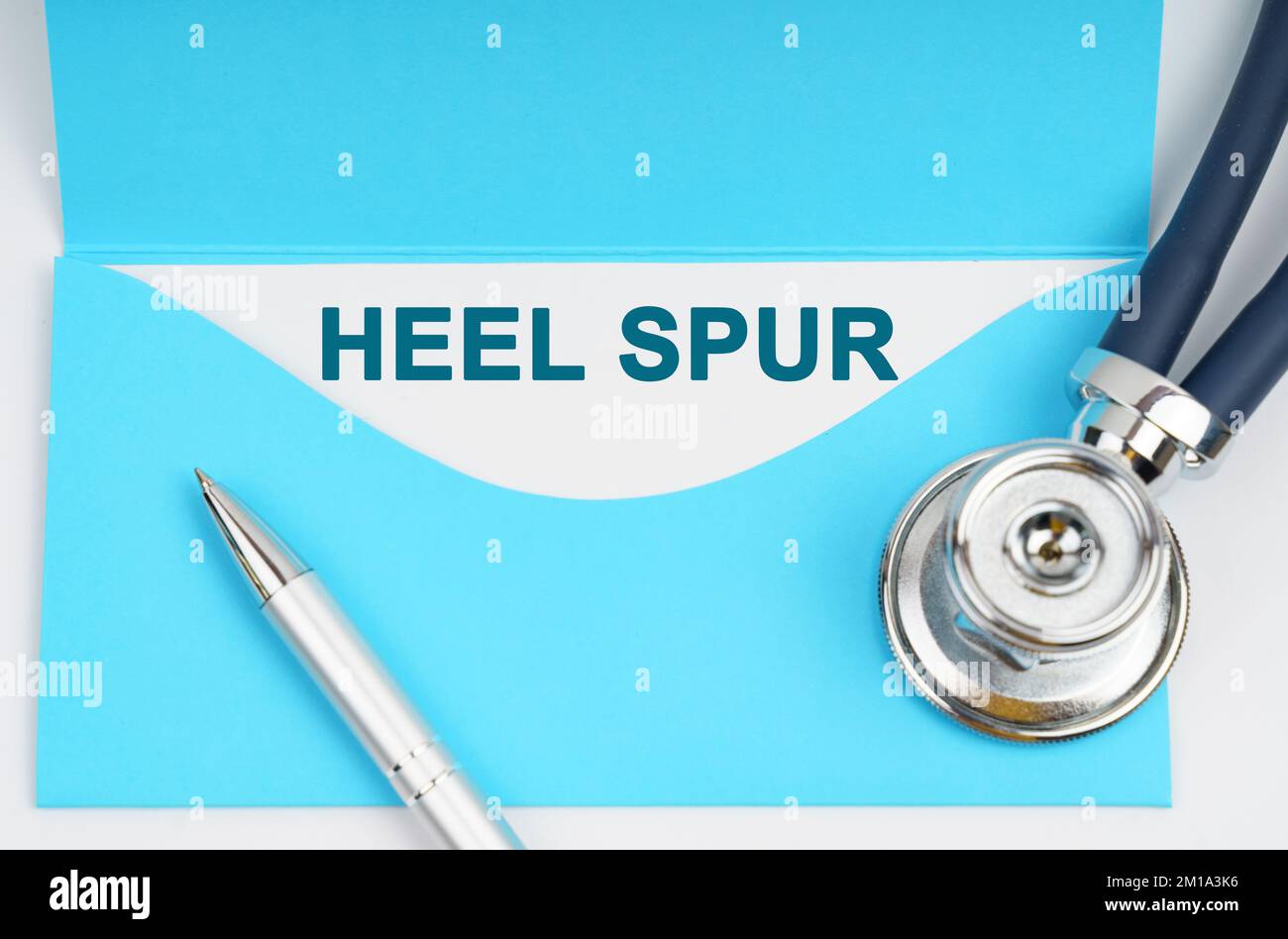 Medicine and health concept. There is a stethoscope on the table, an envelope with paper on which it is written - Heel Spur Stock Photo