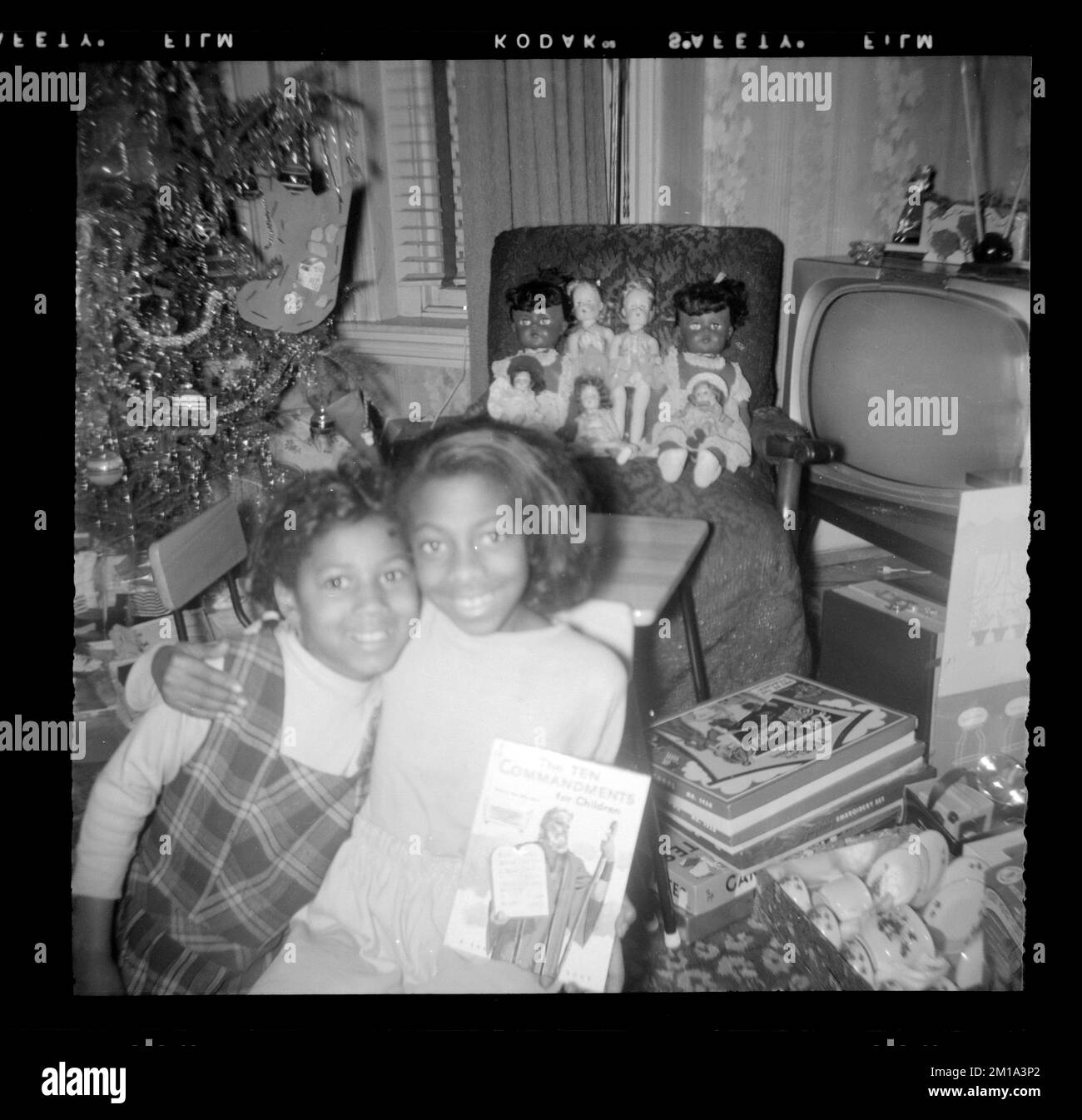 Two girls pose in front of dolls and a Christmas tree , Girls, Dolls