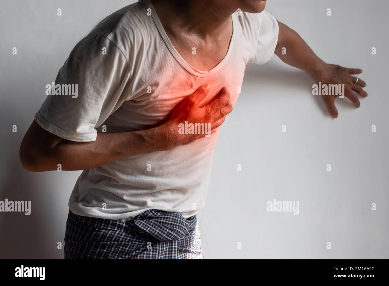 Asian young man suffering from central chest pain. Chest pain can be
