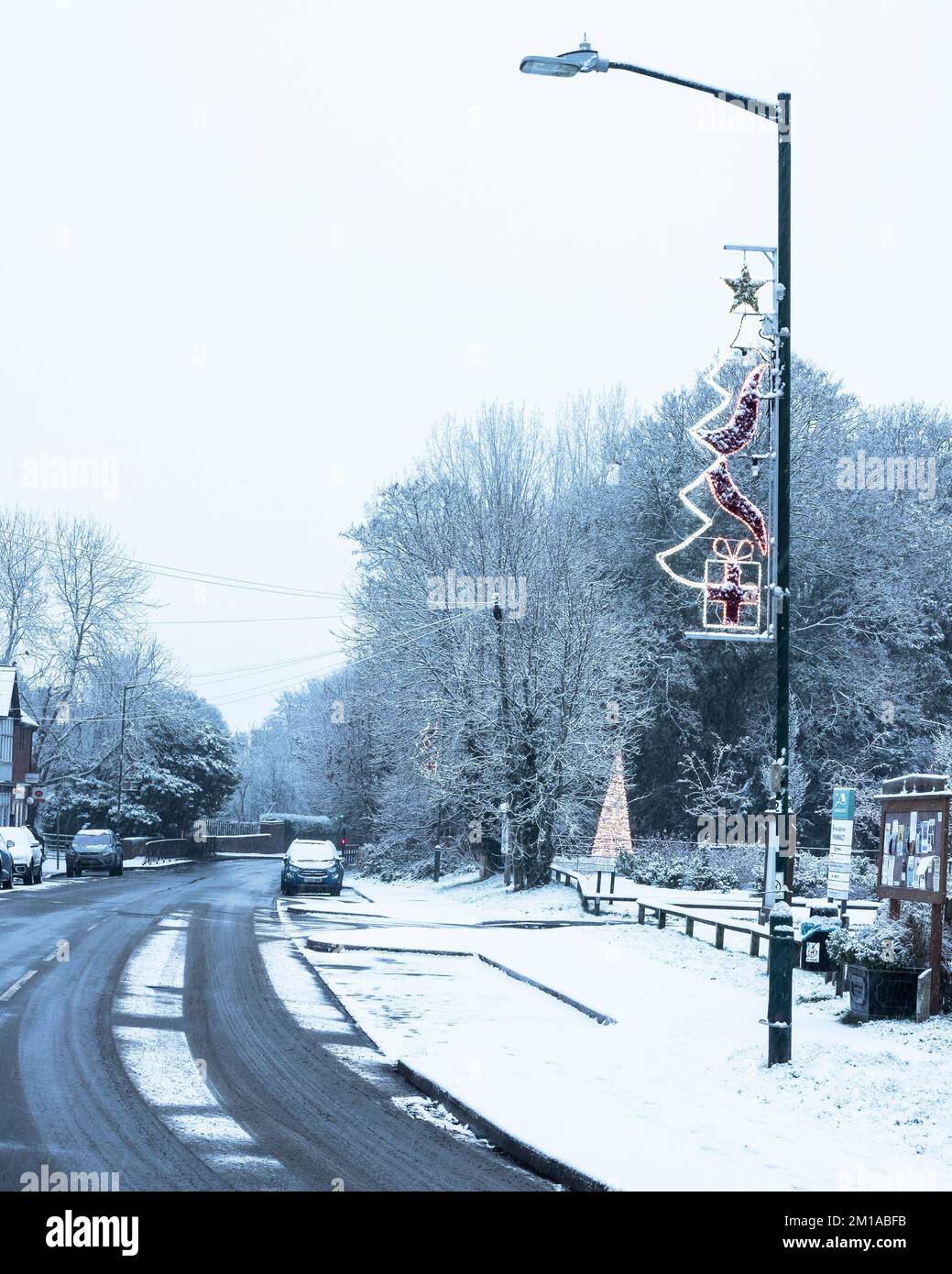 Village snowy winter scene with Christmas decorations. Wellesbourne, England UK. Stock Photo
