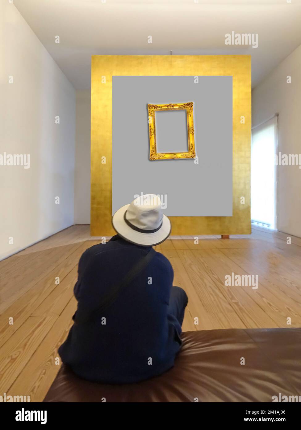 Rear view of a man with cape admiring the golden frame on the wall Stock Photo