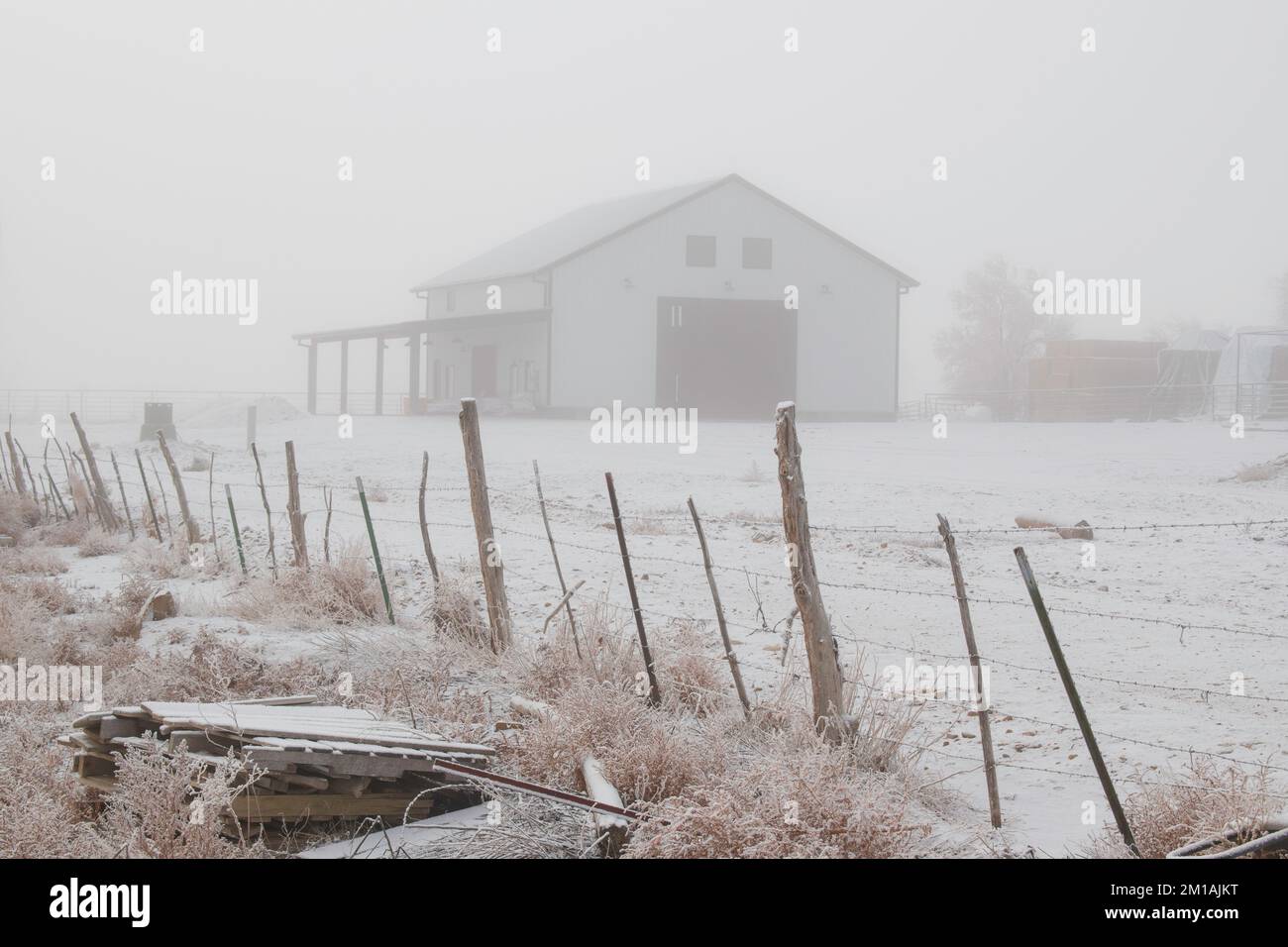 Big White Farm Barn in the Distance on a Cold Foggy Winter Morning Stock Photo