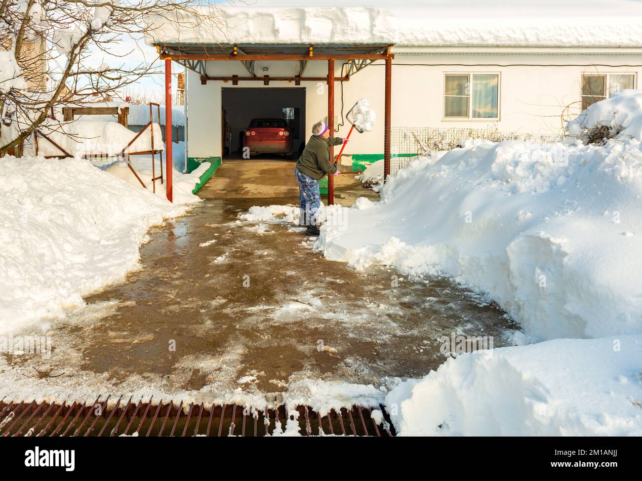 Active elderly man woman pensioner cleans the yard of the house from snow Stock Photo
