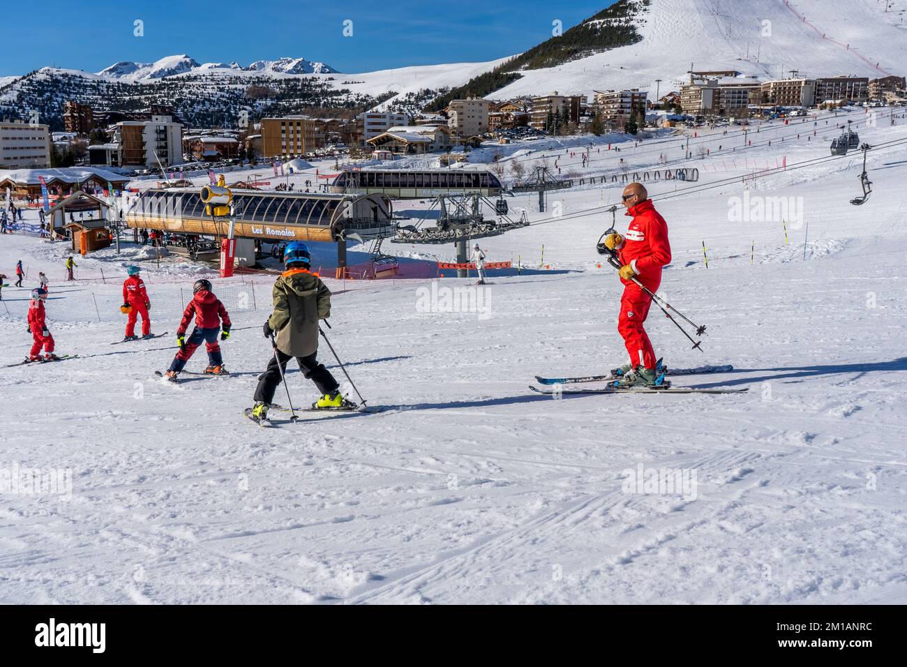 ALPE D'HUEZ, FRANCE - 01.01.2022: Professional ski instructor is teaching a boy to ski on a mountain slope. Snowfall day. Family and children active v Stock Photo