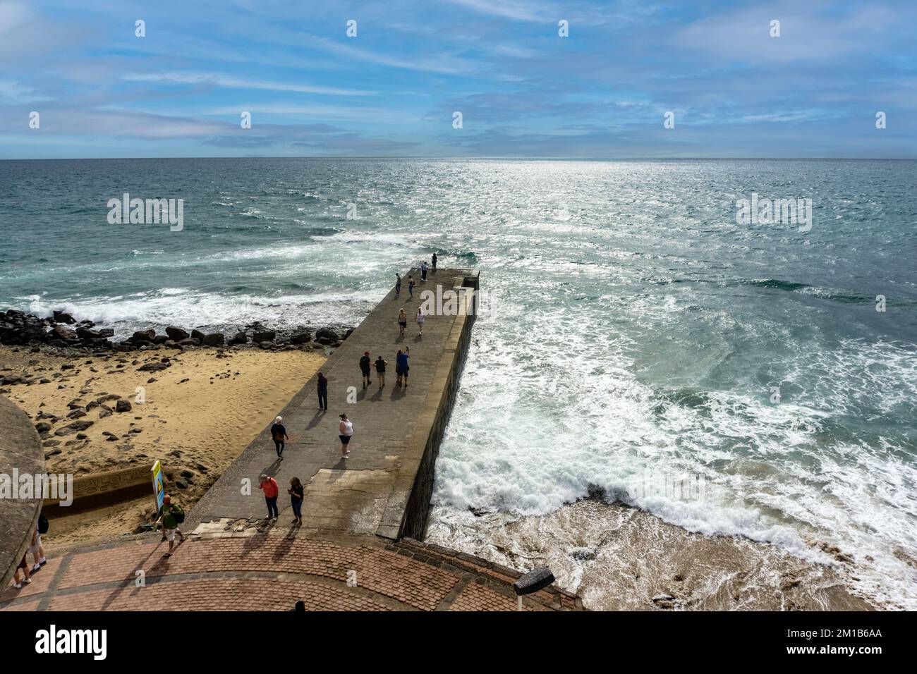 A peaceful moment on the small pier beside Maspalomas Lighthouse, where people enjoy the tranquility of the ocean and the beauty of Gran Canaria Stock Photo