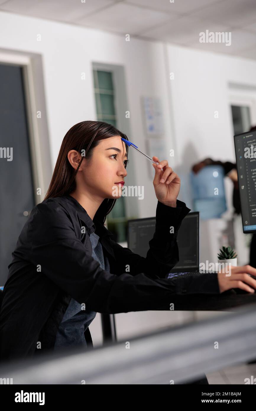 Pensive asian web developer working on html code development and ...