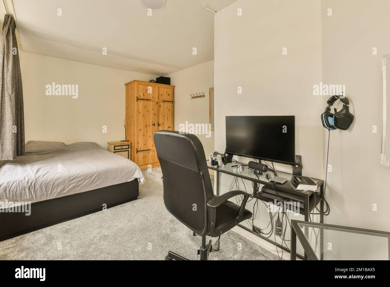 a bedroom with a bed, desk and television set up in the corner of the