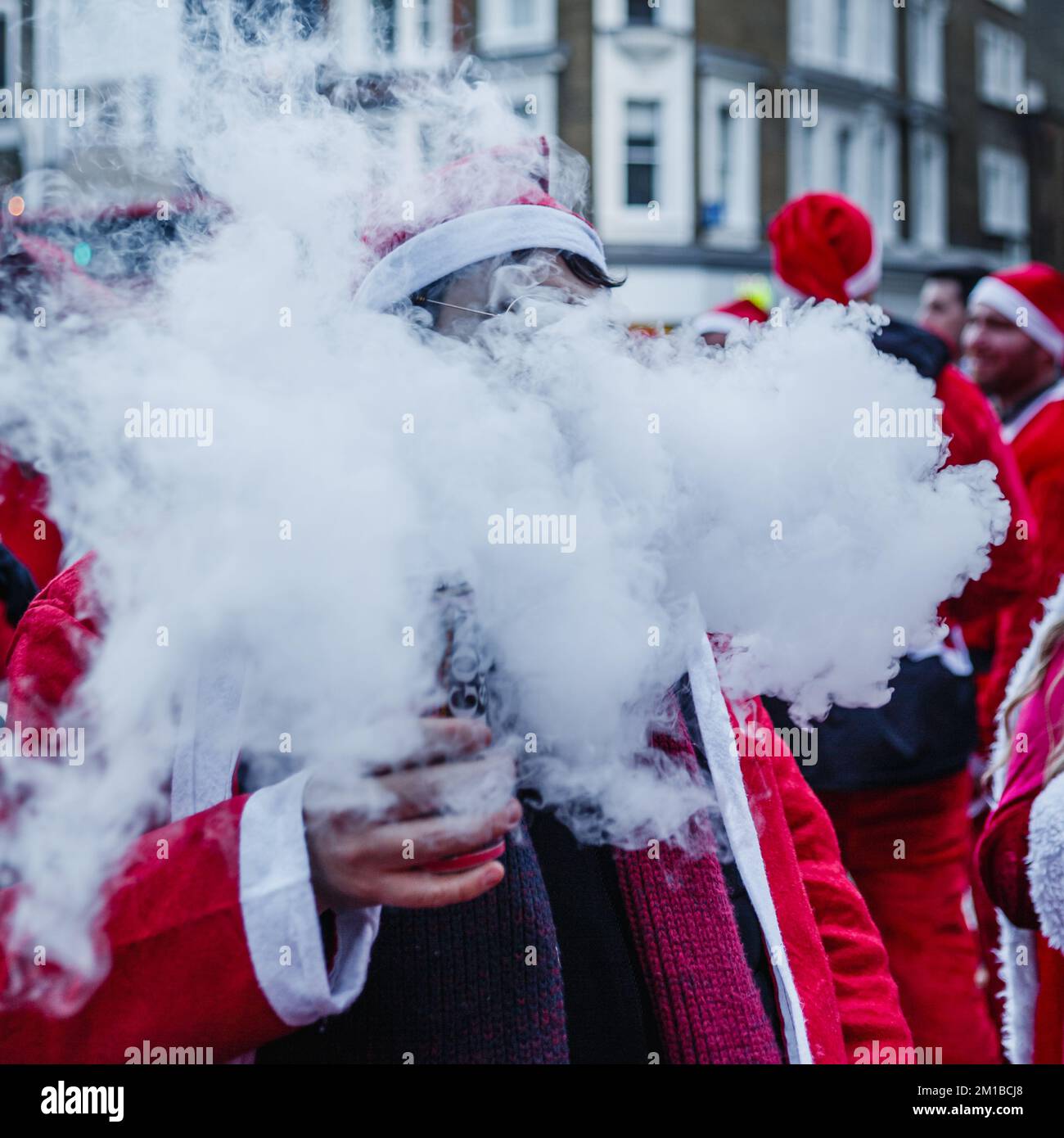 A santa at Santacon exhales a little smoke in London. Stock Photo