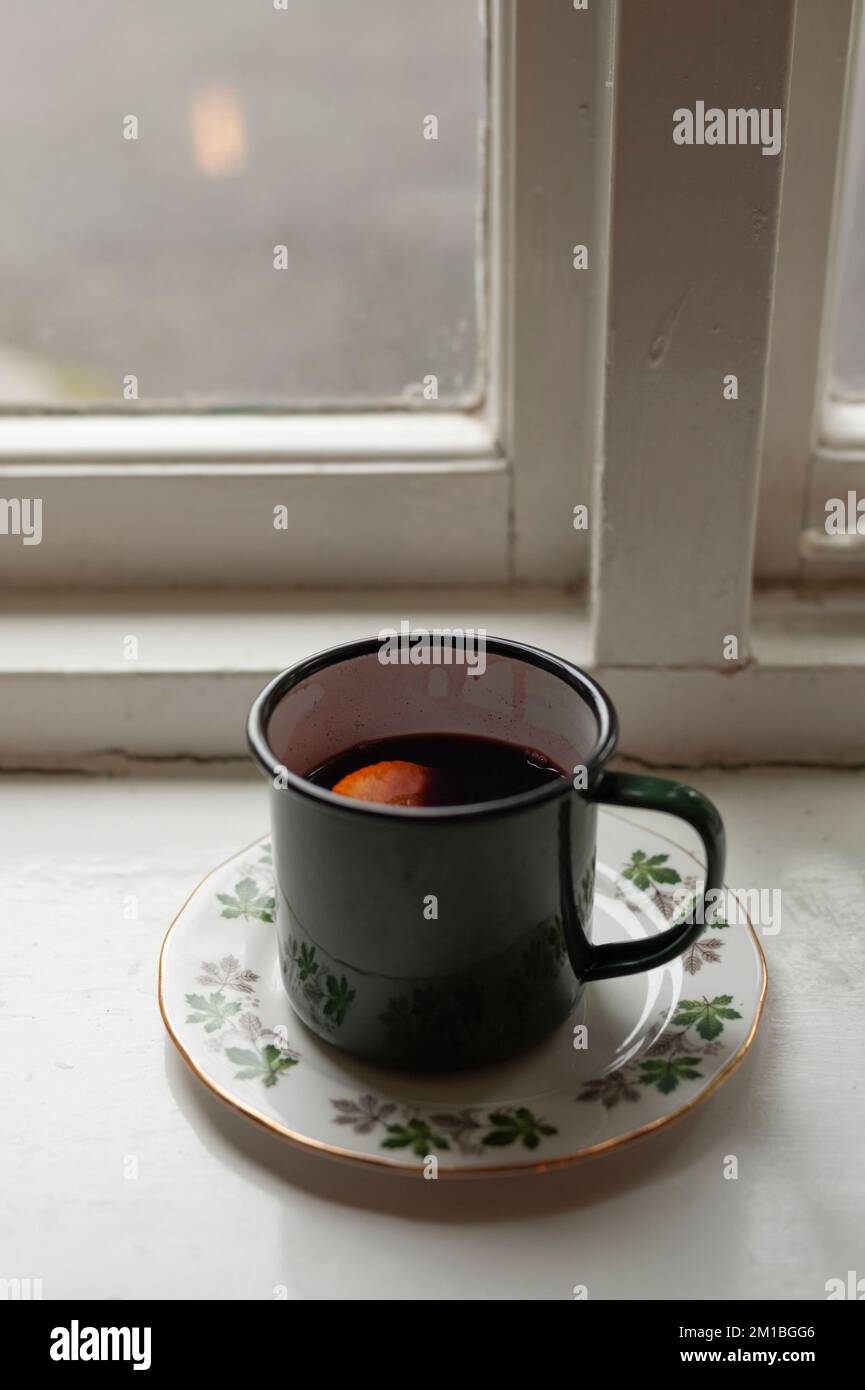 An enamel mug of mulled wine on the windowsill of a pub on a chilly winter’s day in Oxfordshire. Stock Photo