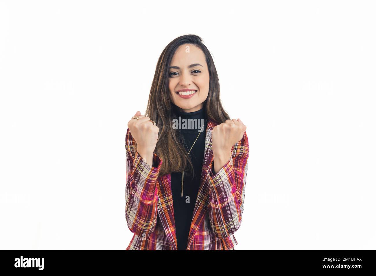 Young latin american woman wearing semi-formal clothes looking into camera with wide smile and lifting both arms in success gesture. Horizontal white background copy space studio shot. High quality photo Stock Photo