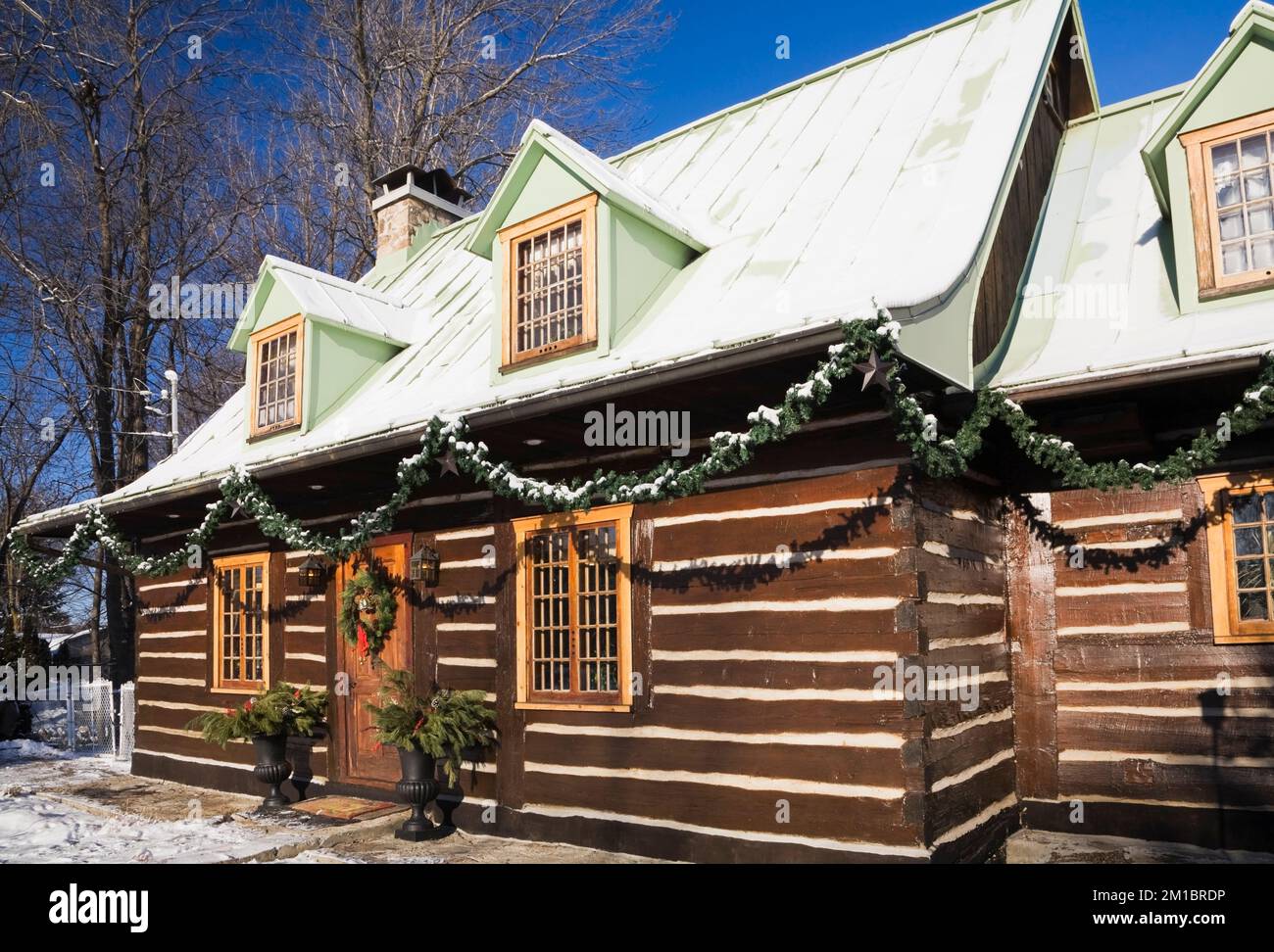 Old 1800s two story Canadiana cottage style log home with Christmas decorations in winter. Stock Photo