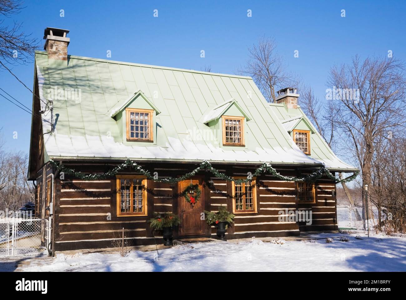 Old 1800s two story Canadiana cottage style log home with Christmas decorations in winter. Stock Photo