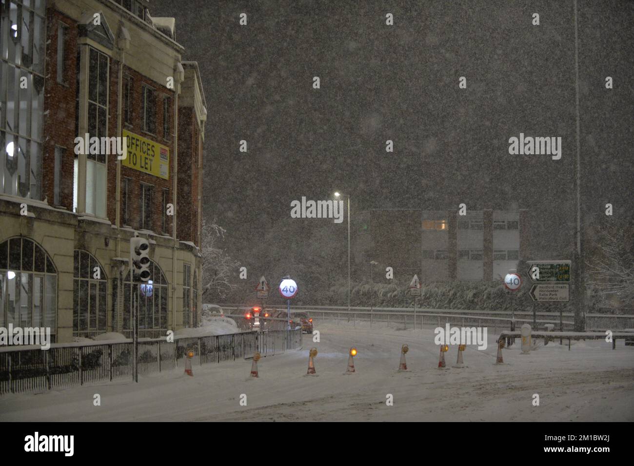 Hertford, UK. 11th December 2022. Heavy snowfall in Hertford, UK causing cars to get stuck on hill leaving the town via the A414 at London Road. People in the cars that had helped decided to put cones across the junction on to London Road to stop other cars getting stuck. Andrew Steven Graham/Alamy Live News Stock Photo
